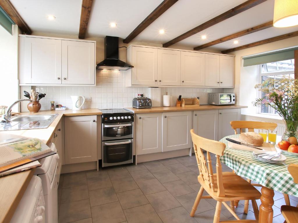 a kitchen with white cabinets and a table with a table sidx sidx sidx at Ty Cerbyd in Cilybebyll