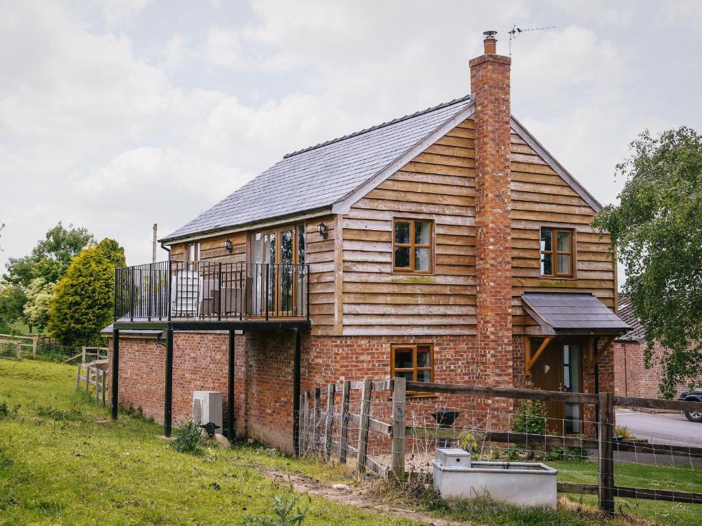 a brick house with a balcony on top of it at Drovers Barn in Malpas