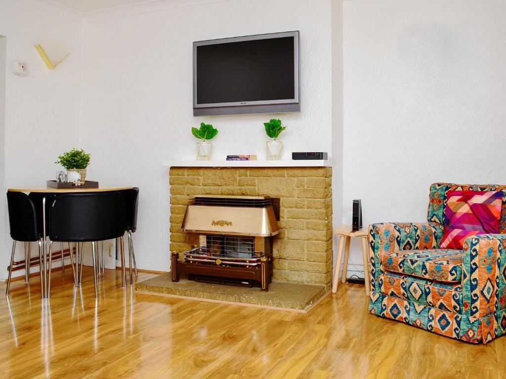 a living room with a fireplace with a television on the wall at St Mary's Crescent House in Stanwell