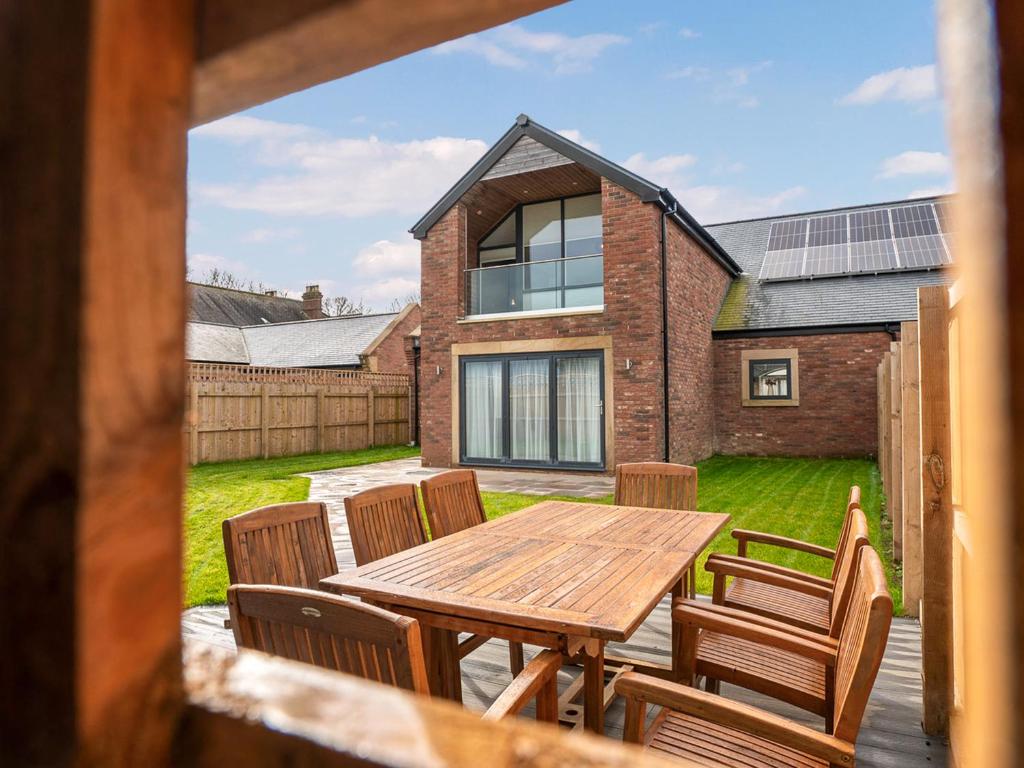a patio with a wooden table and chairs at 12 Galloway - Ukc8975 in Warkworth