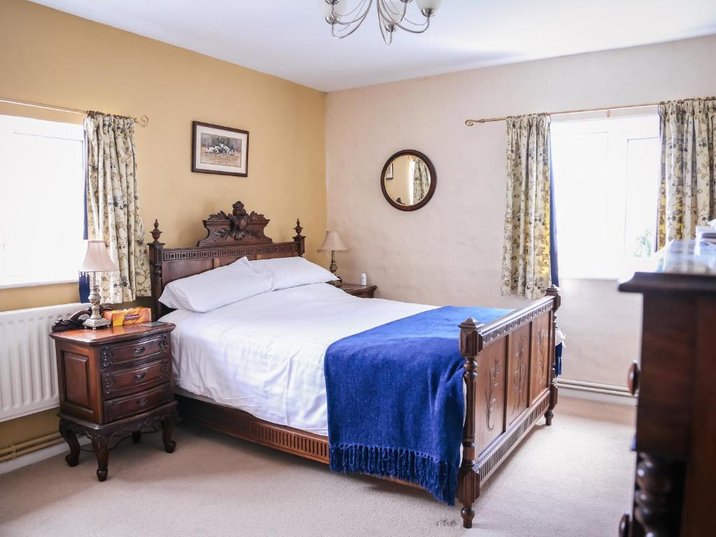 a bedroom with a large bed with a blue blanket at Farmhouse Wing in Malpas