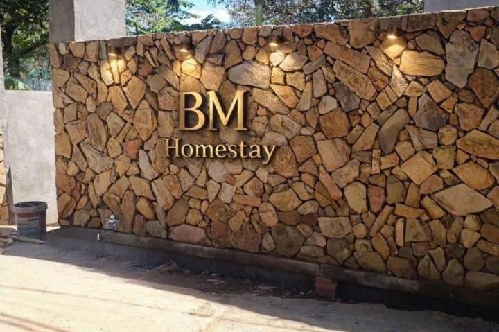 a stone wall with the bm homosasy sign on it at BM homestay in Buôn Dhă Prŏng