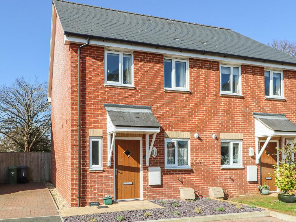 a red brick house with a brown door at Tennyson Cottage in Freshwater