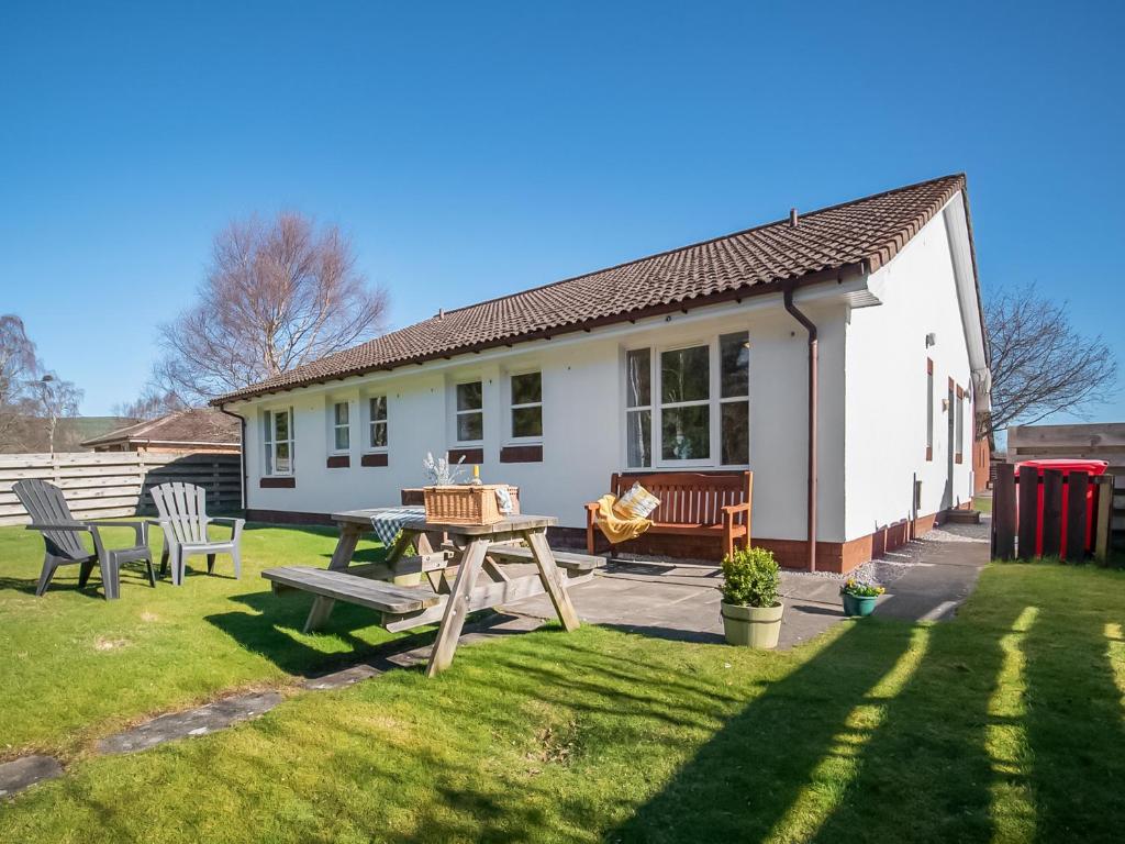 a house with a picnic table and chairs in the yard at Eagle 3 Star - Ukc5056 in Aviemore