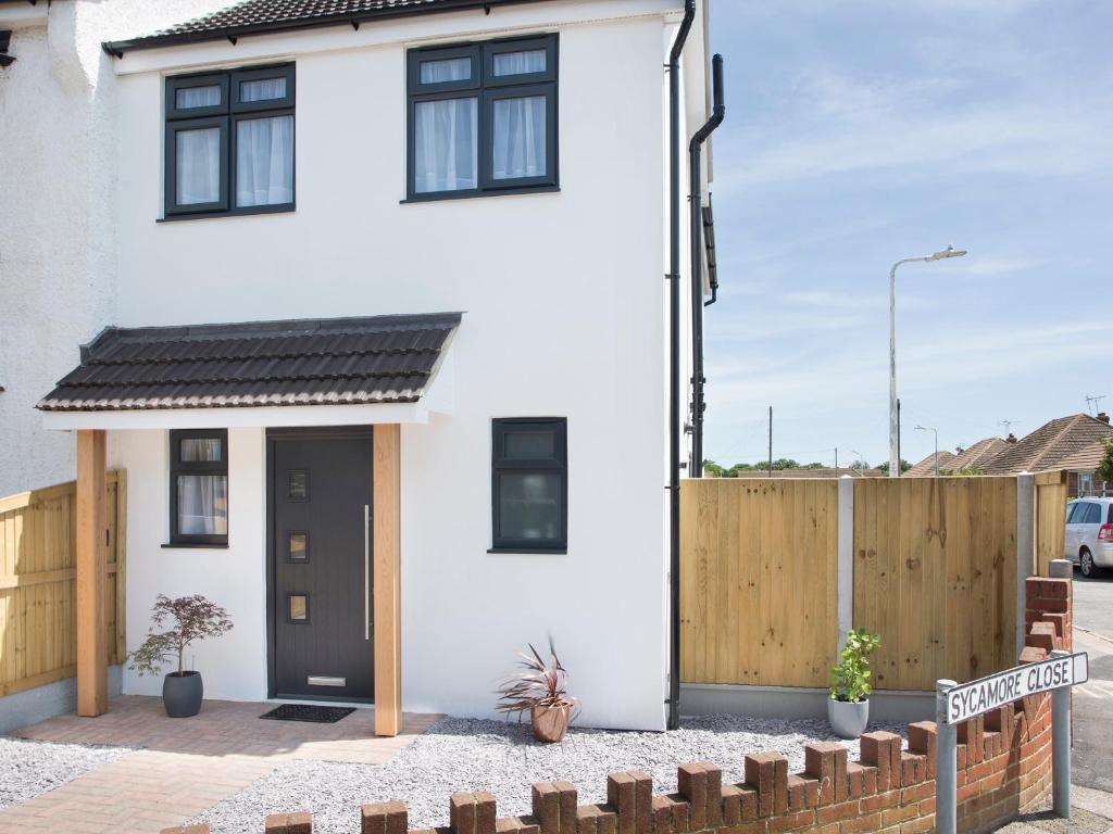a white house with a black door and a wooden fence at Northwood 2 in Broadstairs