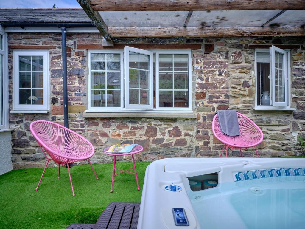 two pink chairs and a tub in front of a house at The Den - Ukc4937 in West Anstey
