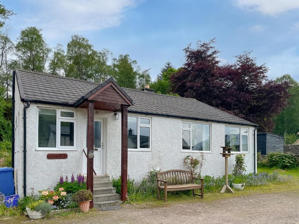 a small white house with a bench in front of it at Crianlarich Cottage in Fort Augustus
