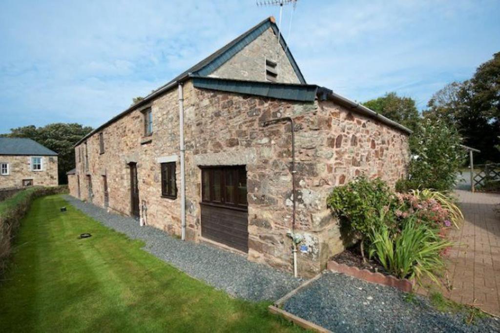 an old brick building with a garage in a yard at Towan Cottage - Cwc79064 in Perranporth