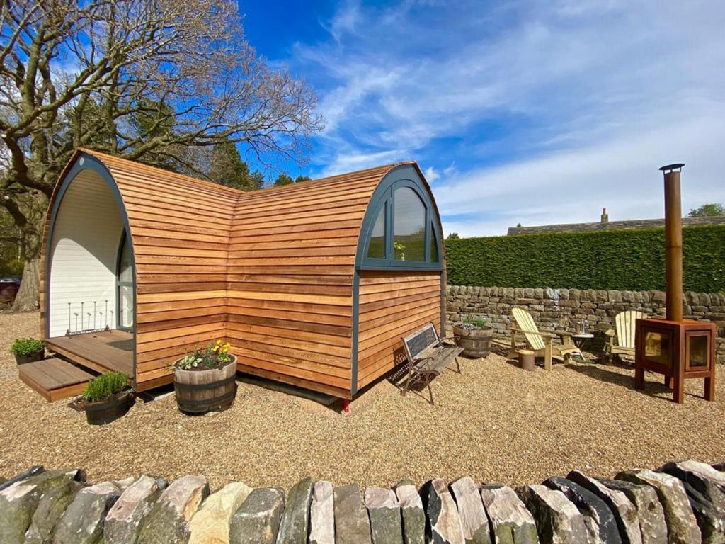 a tiny house in a garden with a stone wall at Oak Tree Retreat in Dronfield