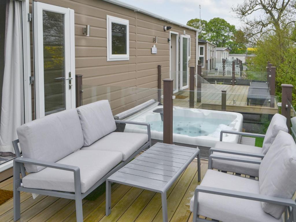 a patio with a couch and a tub on a deck at Unwind 37 - Uk43980 in West Thirston