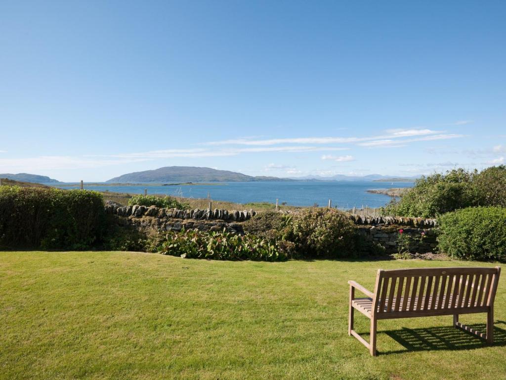 a park bench sitting in the grass near the ocean at Aird House in Ardfern