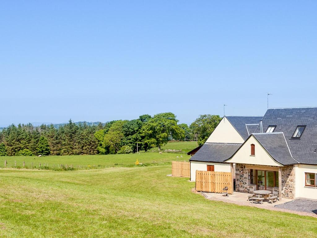a house with a large grassy field in front of it at Beech Cottage - Ukc6252 in Linlithgow