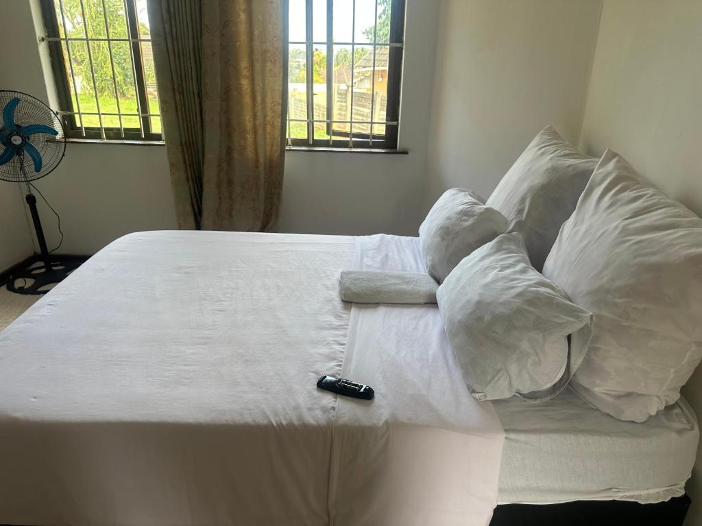 a bed with white sheets and a remote control on it at Empangeni guest house 2 in Empangeni