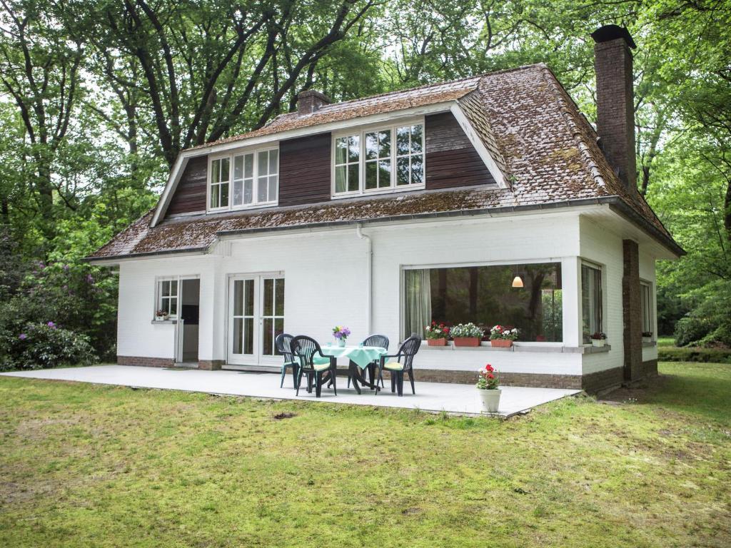 a small white house with a table and chairs at This atmospheric holiday home in Zoersel
