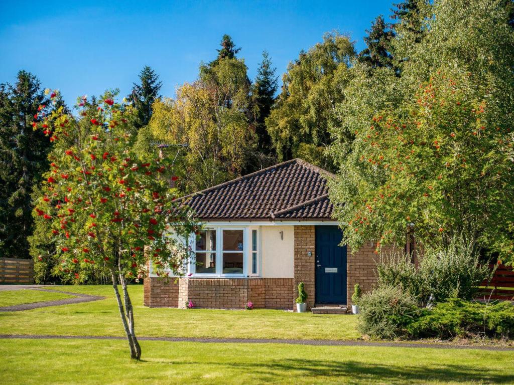 a brick house with a blue door in a yard at The Cairngorm - Ukc5051 in Aviemore