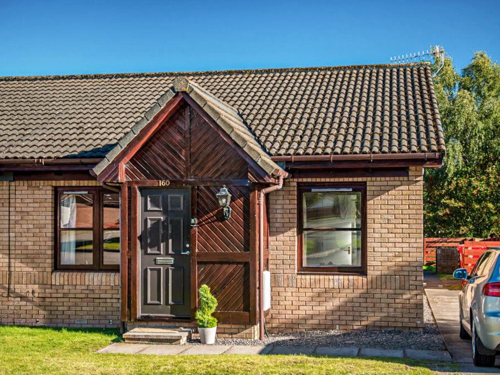 a brick house with a brown door and a window at Munro View - Ukc5040 in Aviemore