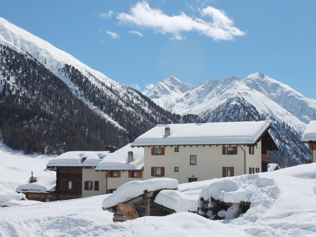 a building covered in snow with mountains in the background at Belvilla by OYO Grit in Livigno