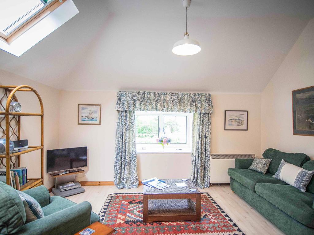 a living room with two green couches and a window at Coachman's Bothy - Ukc5958 in Port Appin