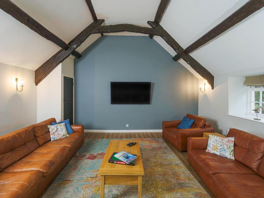 a living room with brown leather couches and a table at Number Six - Ukc4968 in Tawstock