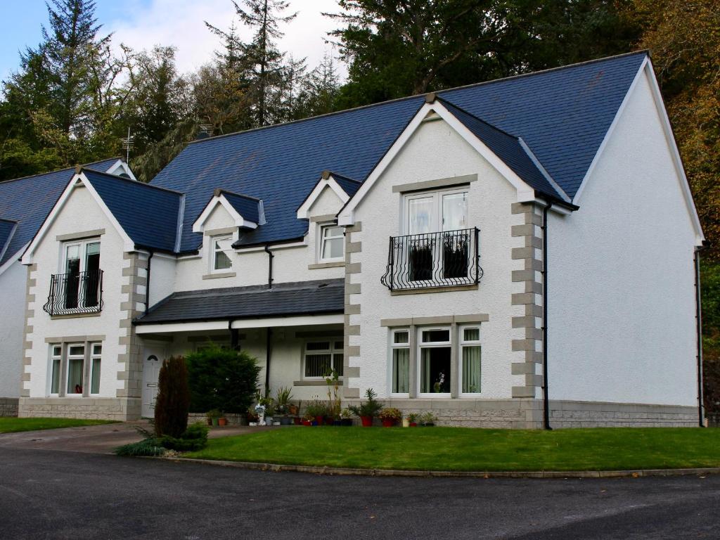 a white house with a blue roof at Pine View in Invergarry
