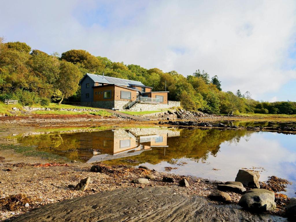 a house on a hill next to a body of water at Dunmore Villa-Uk36498 in Tarbert