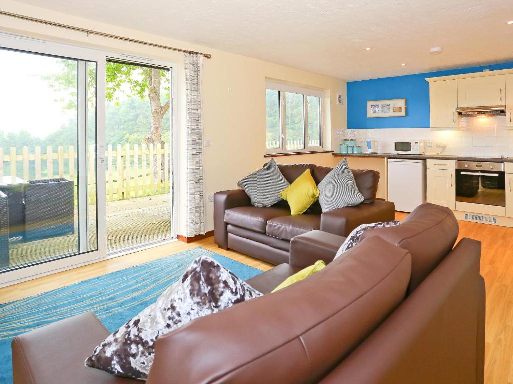 a living room with a couch and a kitchen at Beech Cottage in Uckfield