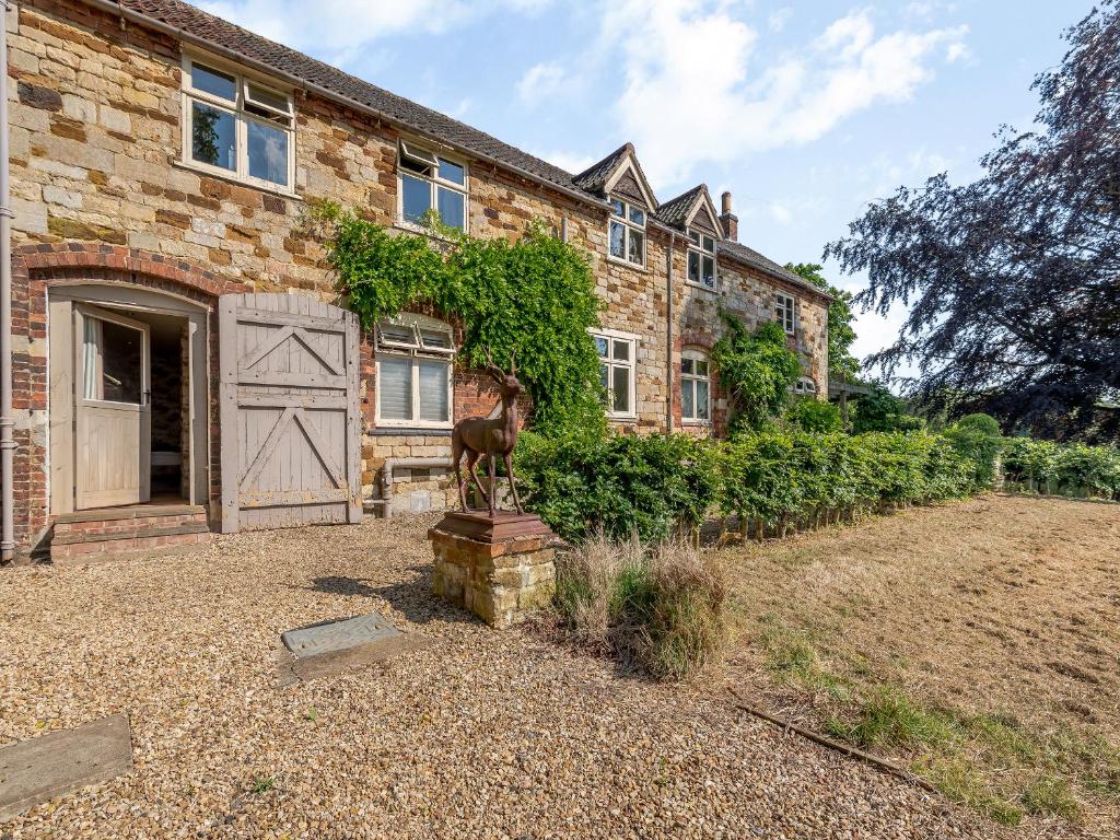 a brick house with a horse statue in front of it at Croxton Lodge & Curlews Nest in Croxton Kerrial