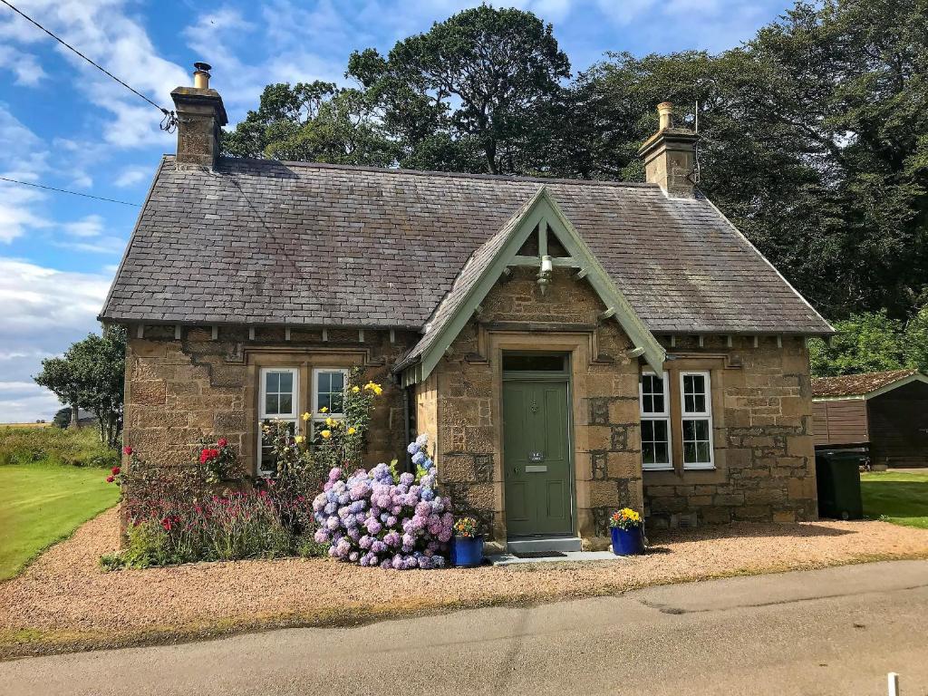 a small house with flowers in front of it at The Lodge in Duffus