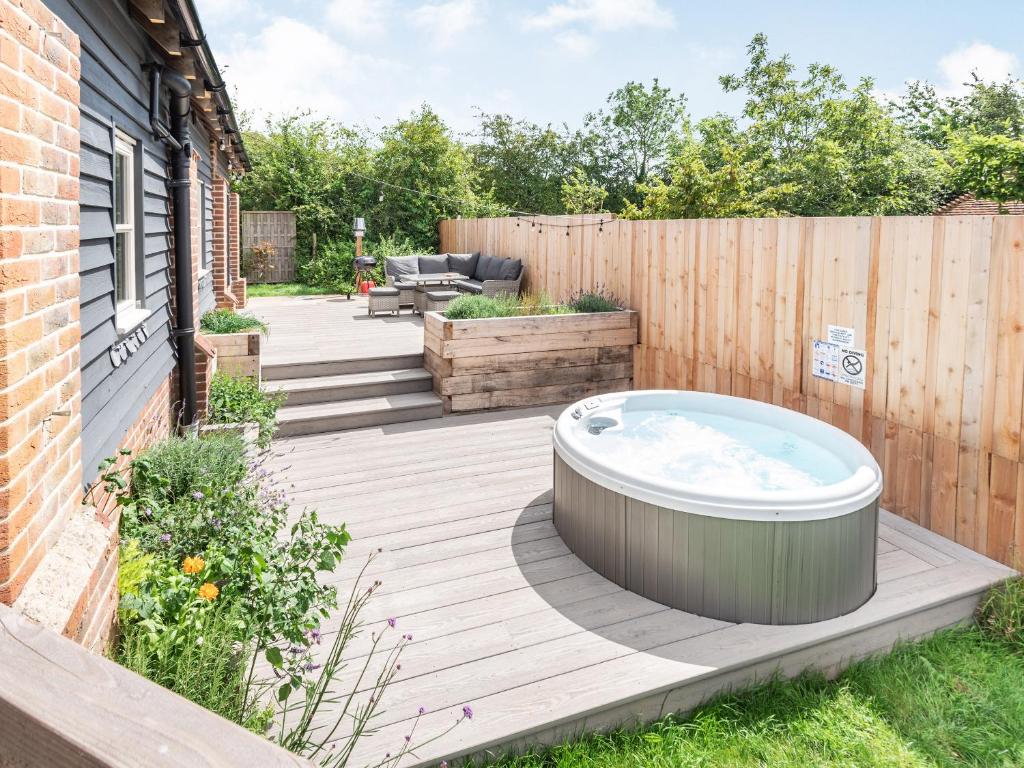 a hot tub on a wooden deck in a backyard at Silhouette's Stable - Uk34102 in Chichester