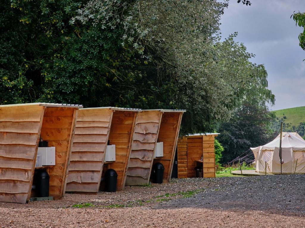 a group of wooden structures sitting next to a tent at Poppy- Ukc4939 in West Anstey