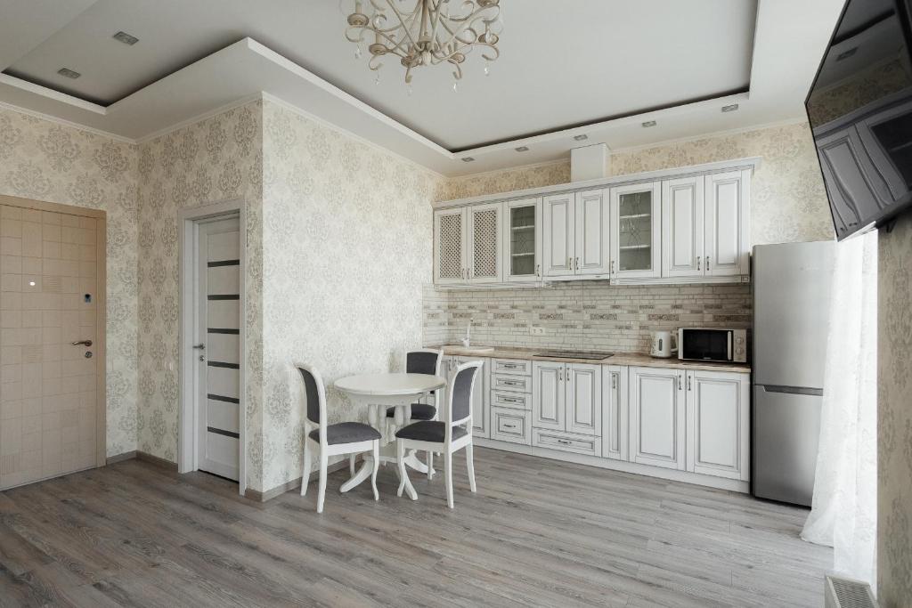 - une cuisine avec des placards blancs, une table et des chaises dans l'établissement City Center Apartment, à Odessa
