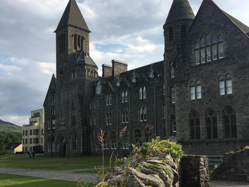 a large stone building with a clock tower at Monastery 13 - Abbots Rest - Ukc4886 in Fort Augustus