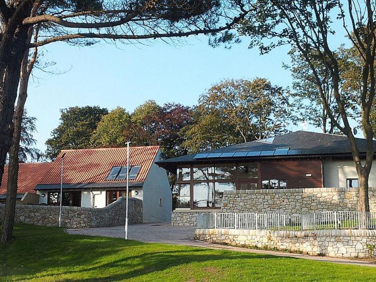 a house with a building with a fence in front of it at Homelands-Cardy in Lundin Links