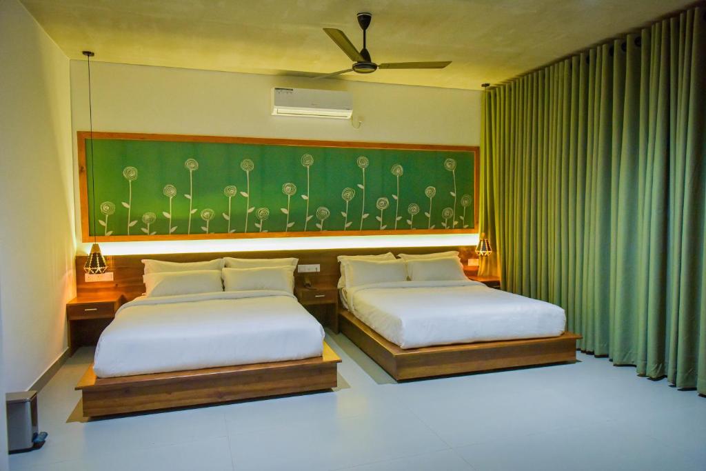 a bedroom with two beds and a green wall at Mistara Ella in Ella