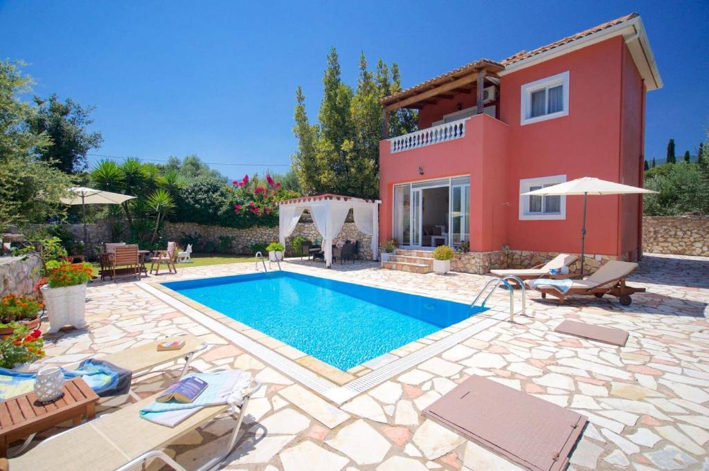 a villa with a swimming pool in front of a house at Villa Marina Epavlis by Villa Plus in Karavomylos
