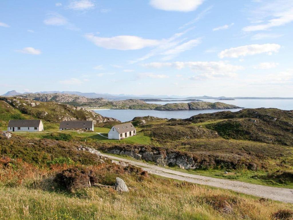 a house on a hill next to a road at Orchid Cottage - Uk5866 in Achmelvich