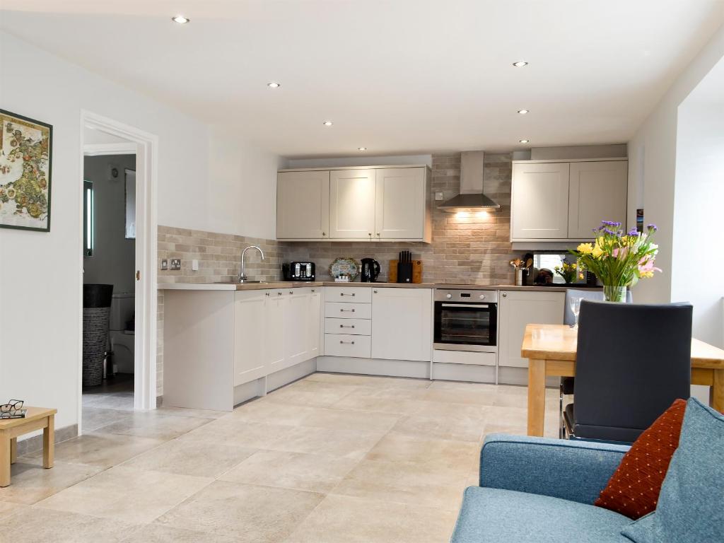 a kitchen with white cabinets and a blue couch at Lloch Lo in Cilybebyll