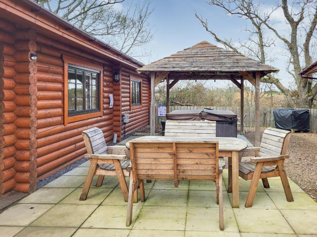 a wooden table and chairs in front of a cabin at Tyne Log Cabin - Uk3480 in West Thirston