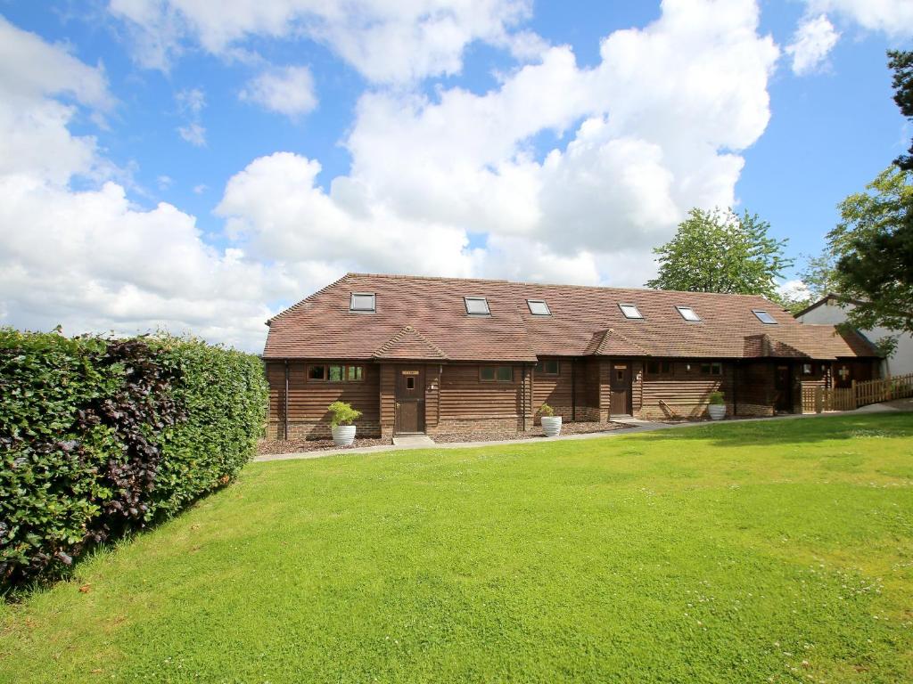 a large wooden barn with a green yard at Cherry Pip in Uckfield