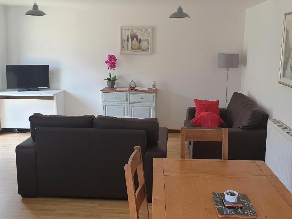 a living room with a black couch and a table at Chestnut Cottage in Uckfield