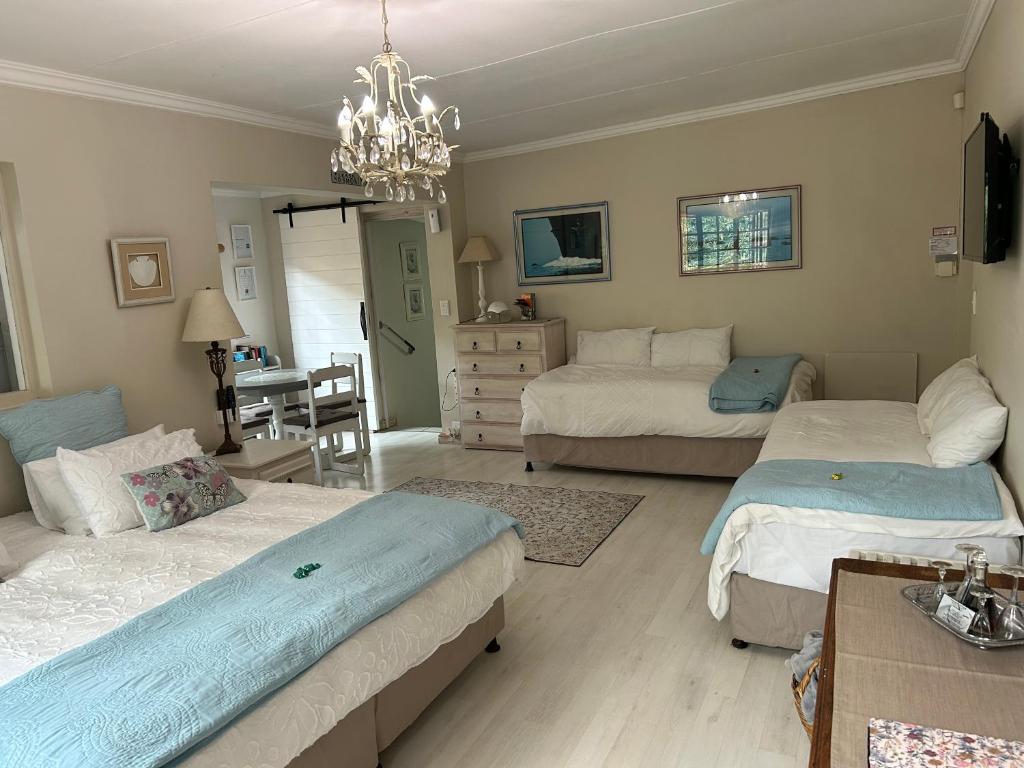 a bedroom with two beds and a chandelier at Twilight Cottage in Plettenberg Bay