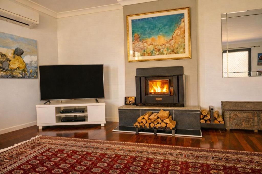 a living room with a fireplace and a tv at Blue Mountains charm with Spa! in Wentworth Falls