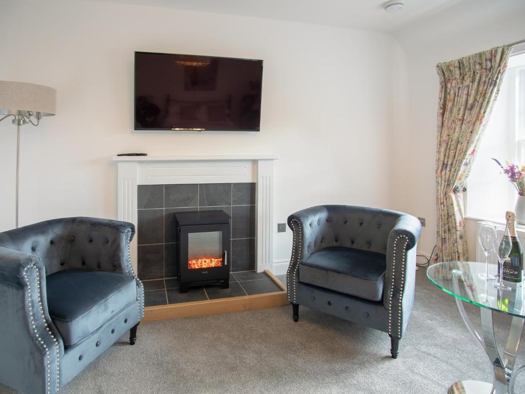 a living room with two chairs and a fireplace at Stableyard Studio - Uk7173 in Carronbridge