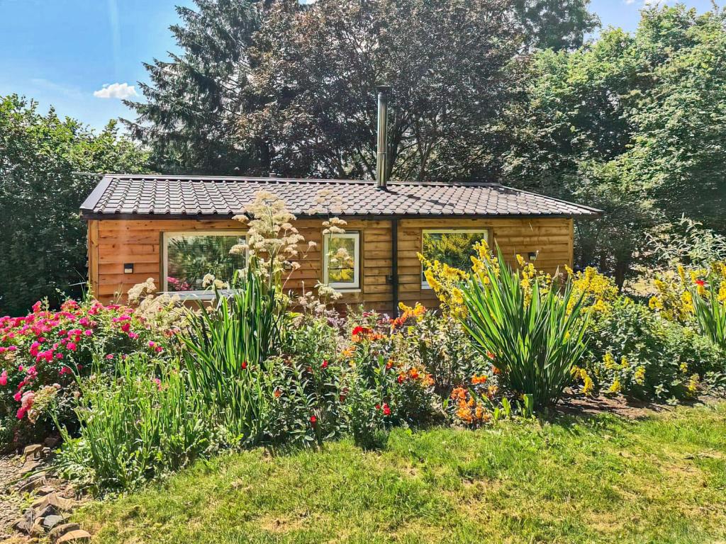 a small log cabin in a garden with flowers at Rowan Tree Lodge - Ukc6977 in Ludlow