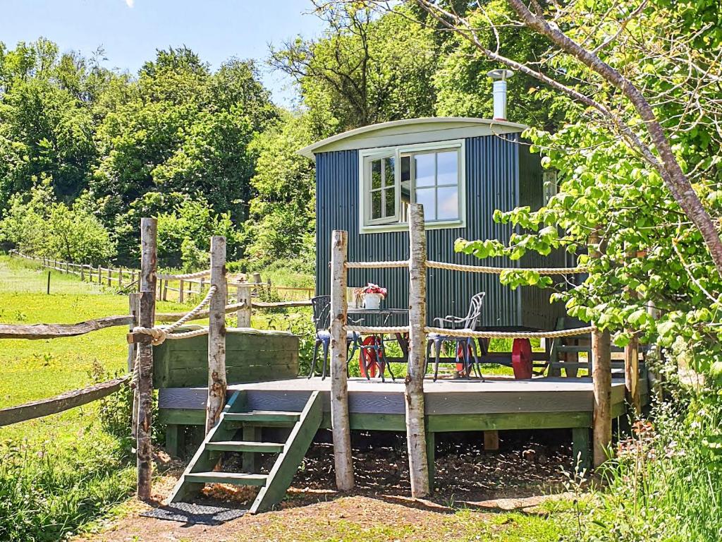 a blue tiny house in a garden with a ladder at Dorset Alpaca Shepherd's Hut in Dorchester