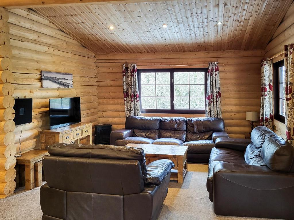 a living room with leather furniture in a log cabin at Tweed Log Cabin-Uk3479 in West Thirston