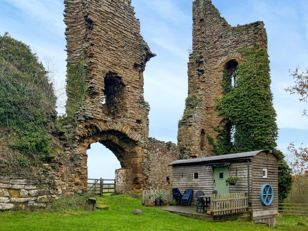 an old castle with a small house in front of it at The Shepherds Hut - Uk50986 in Sheriff Hutton