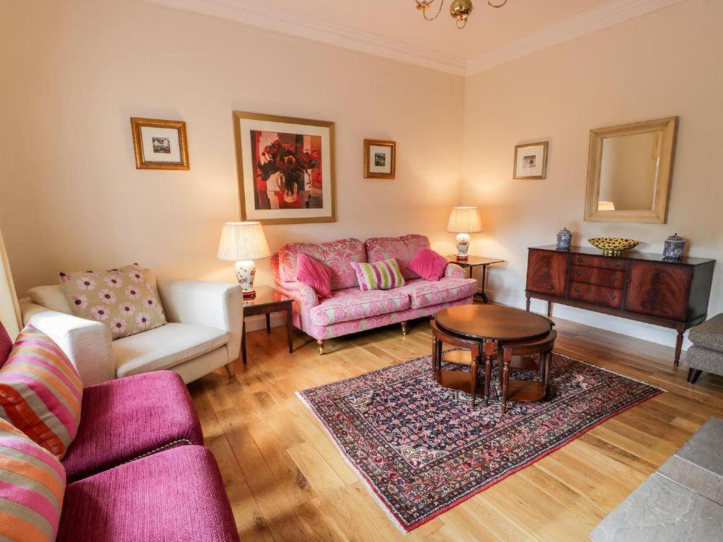 a living room with a pink couch and a table at Gardeners- Uk7233 in Kirkmichael