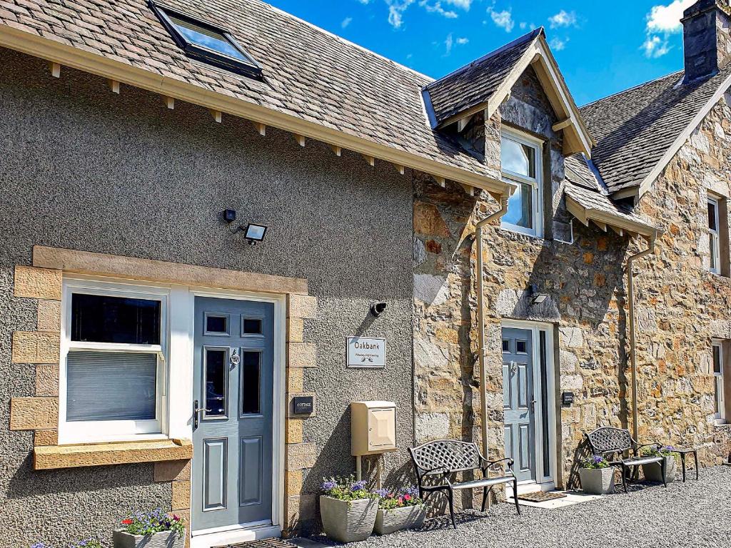 a stone house with a blue door and chairs at Oakbank Cottage - Uk7574 in Pitlochry