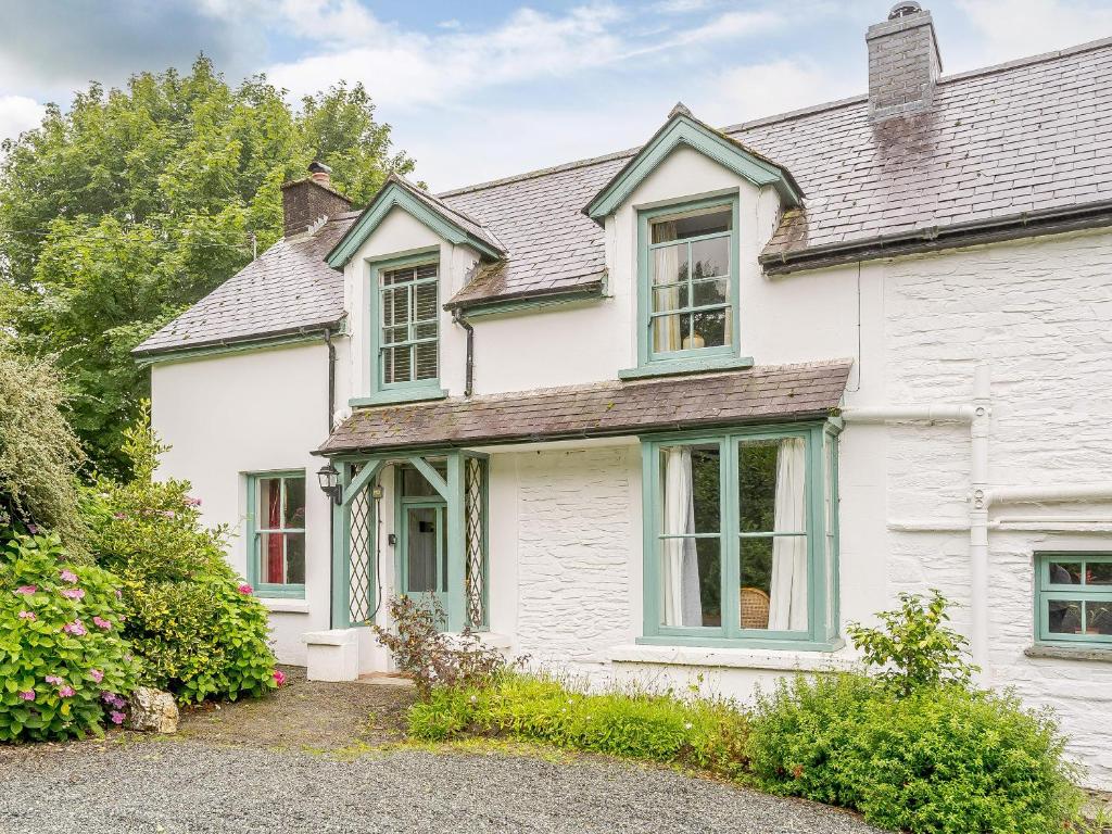 a white house with green windows and bushes at Jasmine Cottage - Uk35245 in Llanfyrnach